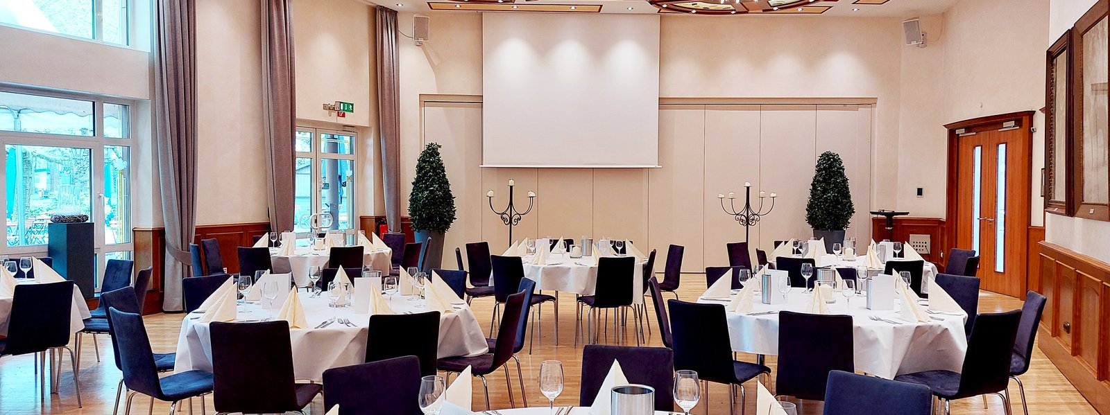 Fahnensaal mit sieben runden Tischen je acht Sitzplätzen, elegant eingedeckt in weiß und creme
