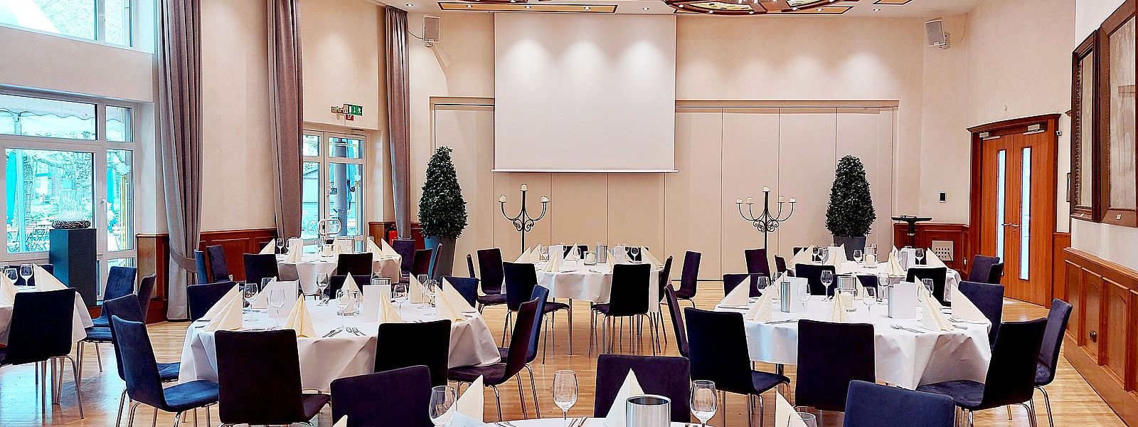 Fahnensaal mit sieben runden Tischen je acht Sitzplätzen, elegant eingedeckt in weiß und creme