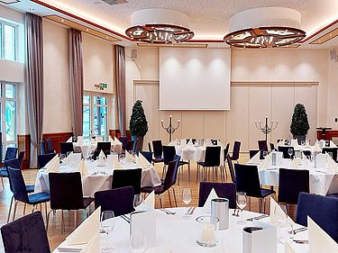 Fahnensaal mit sieben runden Tischen je acht Sitzplätzen, elegant eingedeckt in weiß und creme