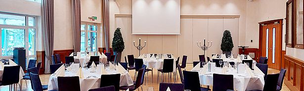 Fahnensaal mit sieben runden Tischen je acht Sitzplätzen, elegant eingedeckt in weiß und creme
