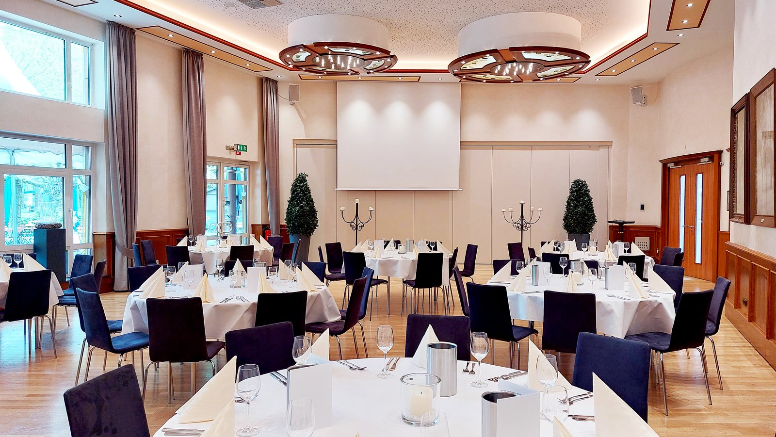 Fahnensaal mit sieben runden Tischen je acht Sitzplätzen, elegant eingedeckt in weiß und creme
