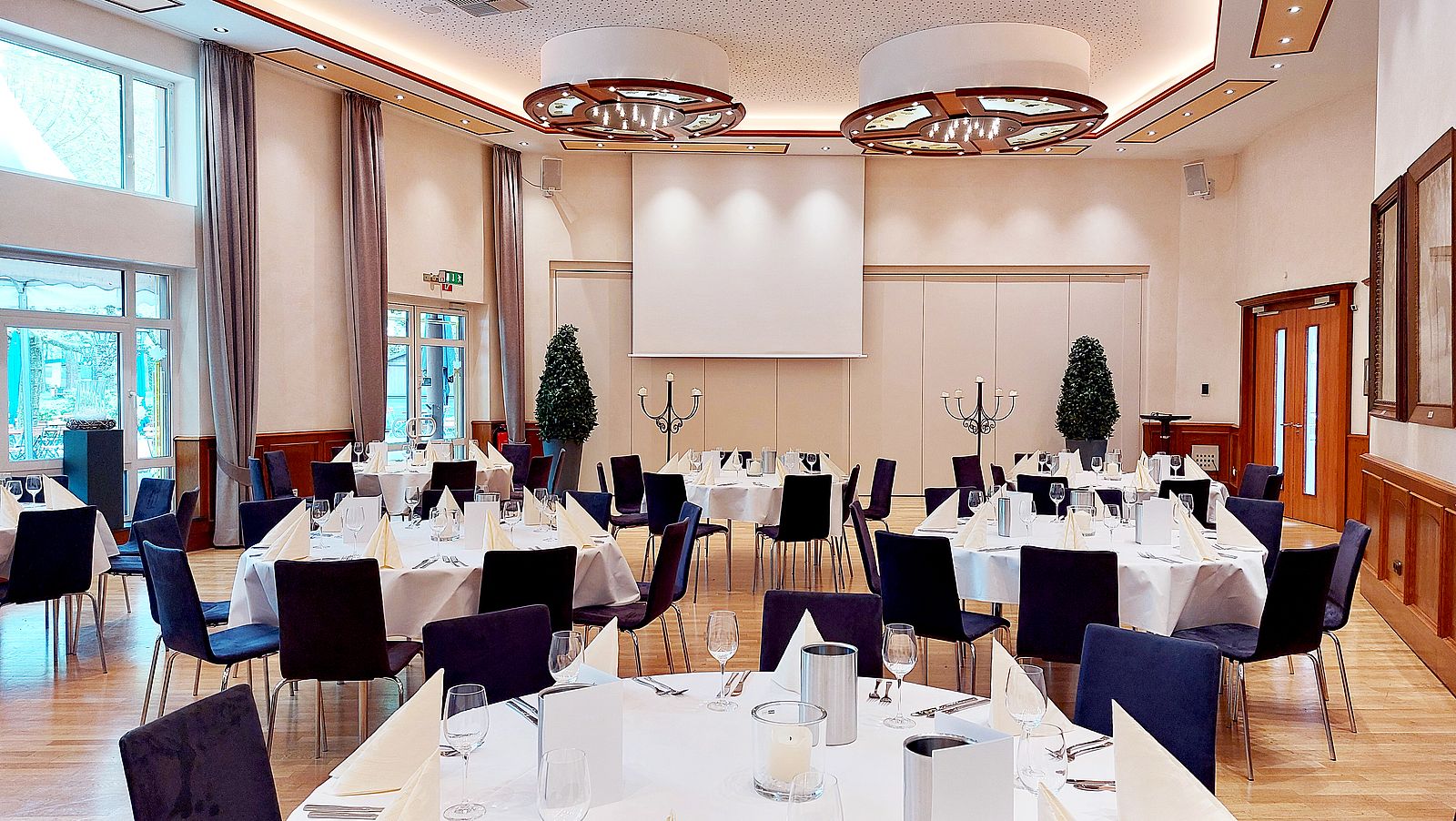 Fahnensaal mit sieben runden Tischen je acht Sitzplätzen, elegant eingedeckt in weiß und creme