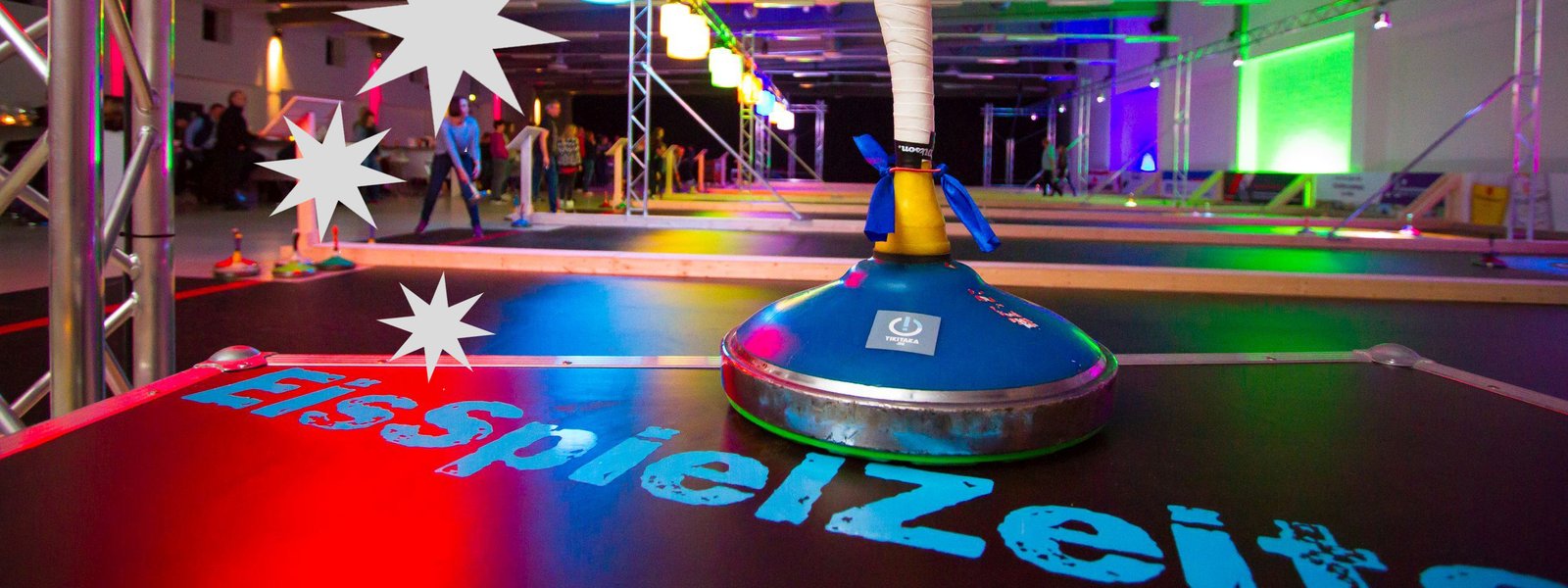 Großaufnahme eines Eisstocks mit den bunt beleuchteten Kunststoffbahnen im Hintergrund
