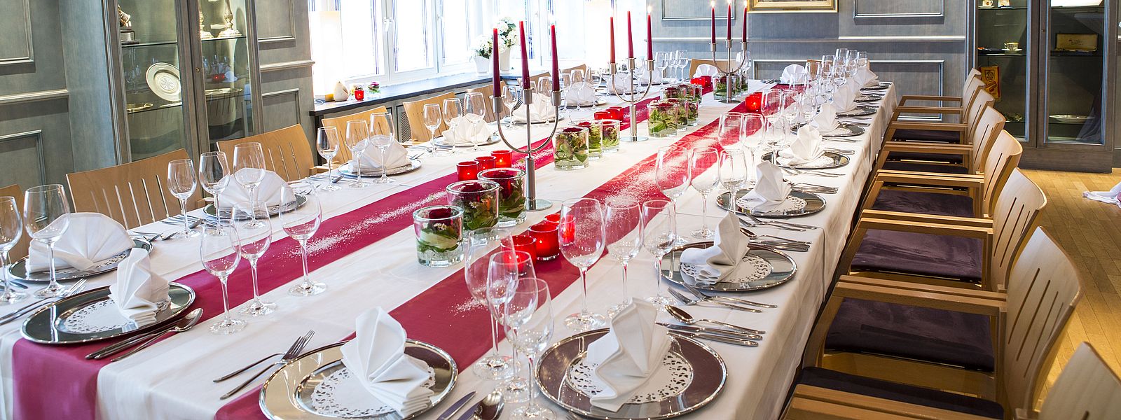 Festtafel im Blauen Zimmer mit silbernen Platztellern und rot-weißer Dekoration