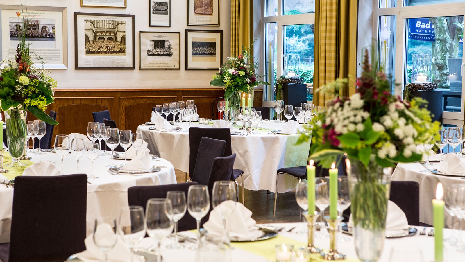 Eingedeckte runde Tische im Fahnensaal mit auffälligem bunten Blumenschmuck