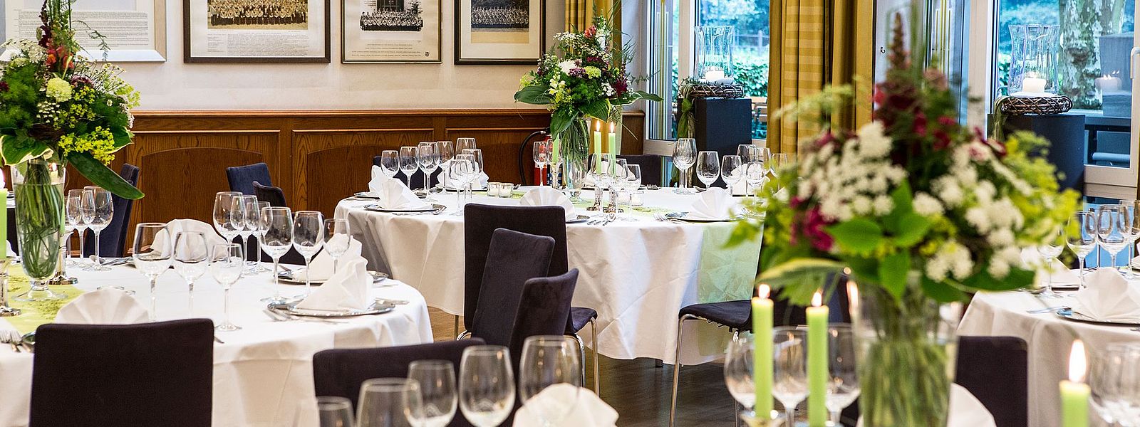 Eingedeckte runde Tische im Fahnensaal mit auffälligem bunten Blumenschmuck 