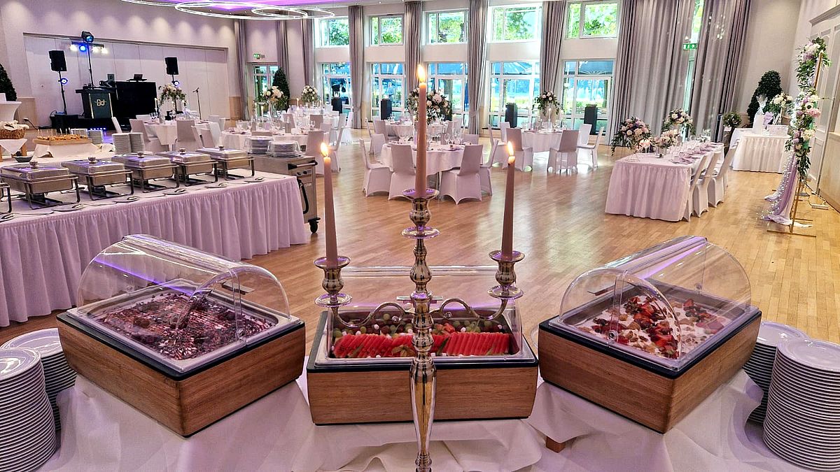 Der Andreas-Ferrarisaal als Hochzeitssaal mit runden Tischen, kleiner Bühne für den DJ und dem Buffet im Vordergrund