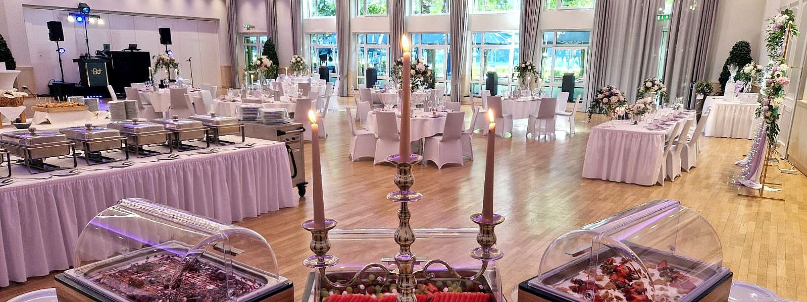 Der Andreas-Ferrarisaal als Hochzeitssaal mit runden Tischen, kleiner Bühne für den DJ und dem Buffet im Vordergrund