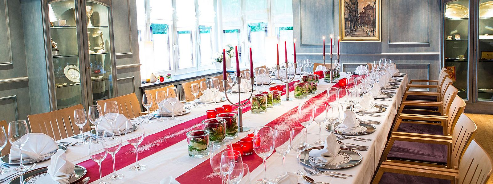 Festtafel im Blauen Zimmer mit silbernen Platztellern und rot-weißer Dekoration