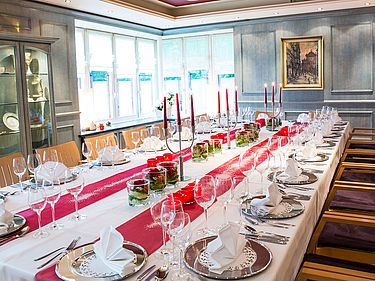 Festtafel im Blauen Zimmer mit silbernen Platztellern und rot-weißer Dekoration