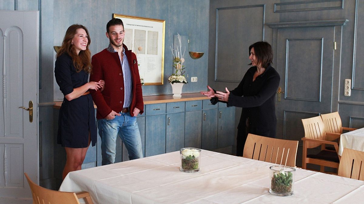 Veranstaltungsleitung Edith Hustadt präsentiert einem jungen Paar das Blaue Zimmer